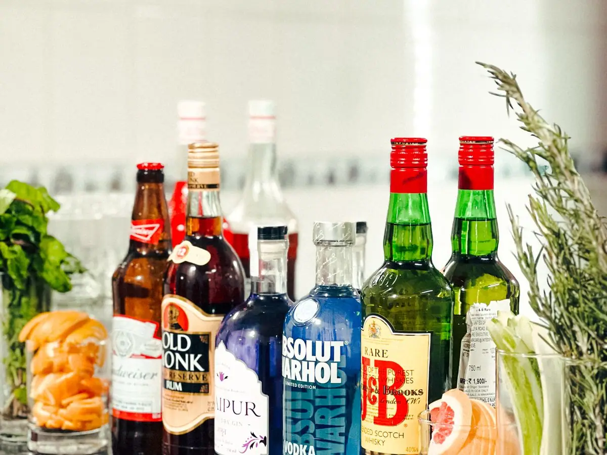 Polished bar counter lined with crystal glassware and bitters bottles under brass pendant lighting