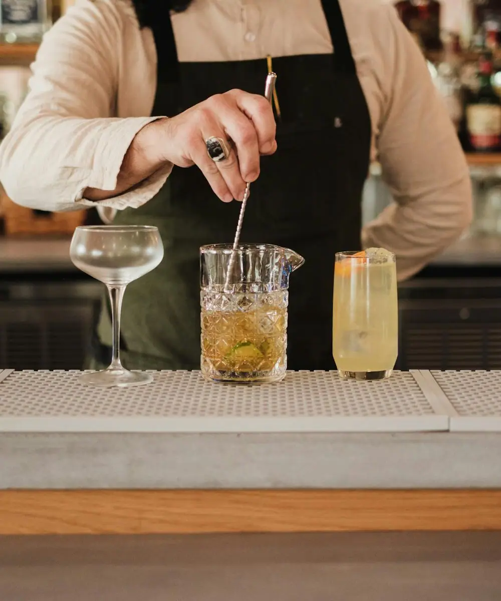 Close-up of a bartender expressing citrus oils and adding a fresh garnish to a finished cocktail