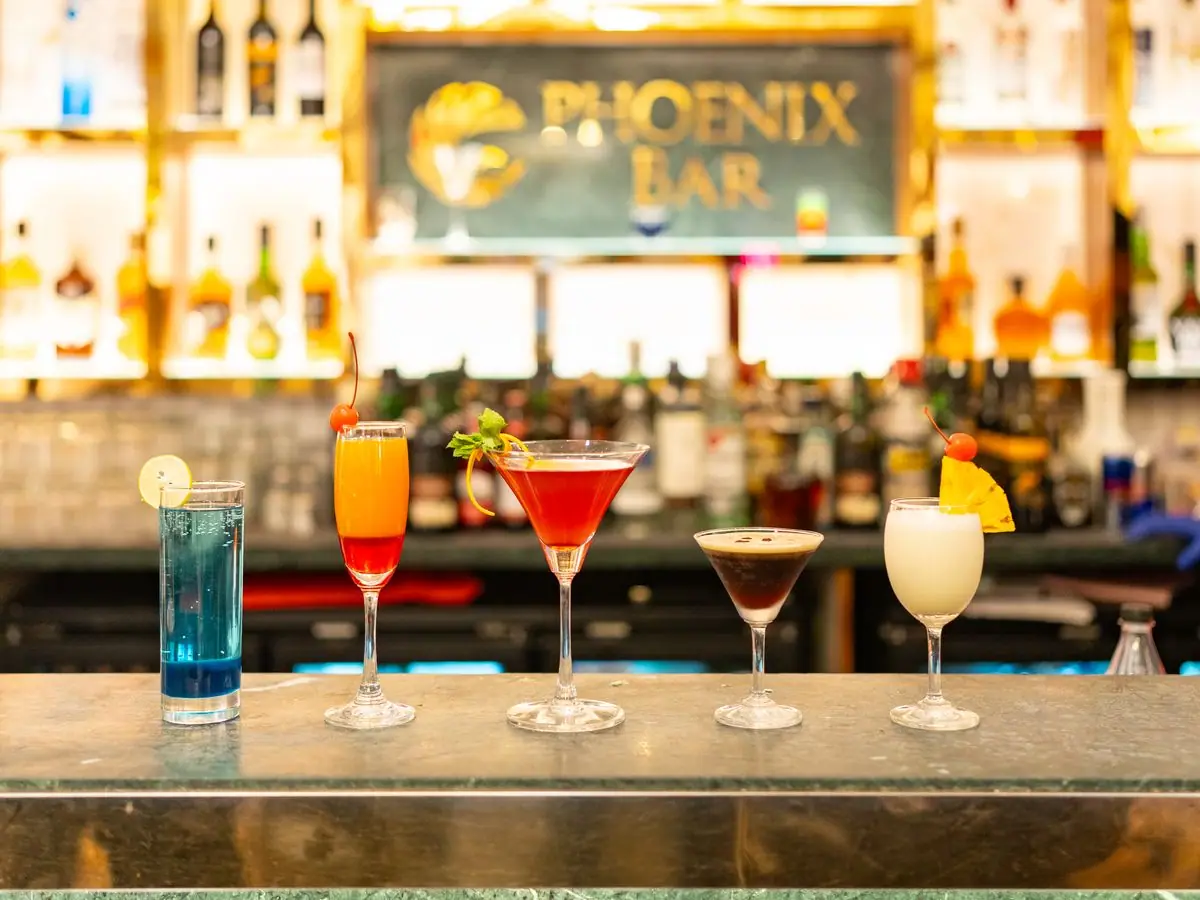 Intimate bar lounge bathed in warm amber light with deep purple velvet booths and low candlelit tables